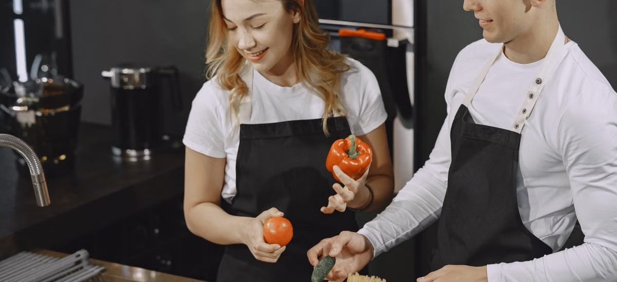 Young couple preparing meal in a modern kitchen, smiling and enjoying time together.