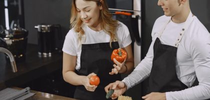 Young couple preparing meal in a modern kitchen, smiling and enjoying time together.