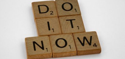 Wooden scrabble tiles forming 'DO IT NOW' on a minimal white backdrop. Inspiring concept.