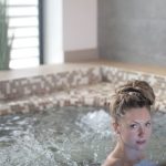 Woman enjoying a relaxing soak in a modern indoor spa jacuzzi.