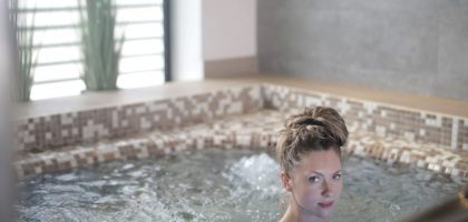 Woman enjoying a relaxing soak in a modern indoor spa jacuzzi.